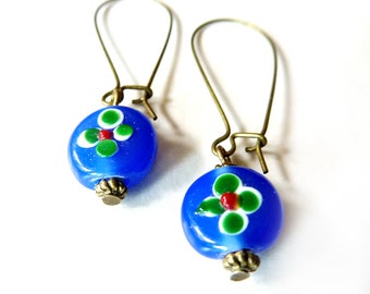 Bronze-colored earrings with XL ear hooks, fitted with a blue handmade glass bead with a floral pattern