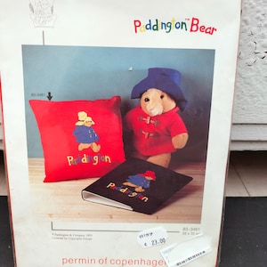 Könnte beinhalten: Ein Bastelset mit Paddington Bär. Das Set enthält ein rotes Kissen und ein schwarzes Notizbuch, beide mit Paddington Bär-Designs bestickt. Das Set enthält auch ein Paddington Bär-Plüschtier.