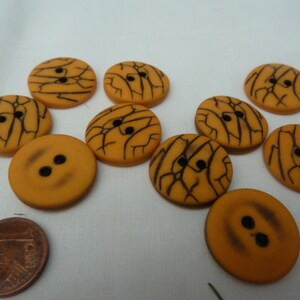 May include: Ten orange buttons with black crackle design. Some buttons have two holes, others have four holes.