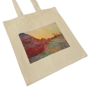 Può includere: Una borsa tote con un'immagine stampata di un campo di balle di fieno al tramonto. Le balle di fieno sono di colore marrone rossiccio e il cielo è di un arancione e giallo vibrante.