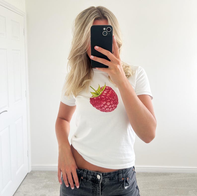 May include: White t-shirt with a red raspberry graphic print.