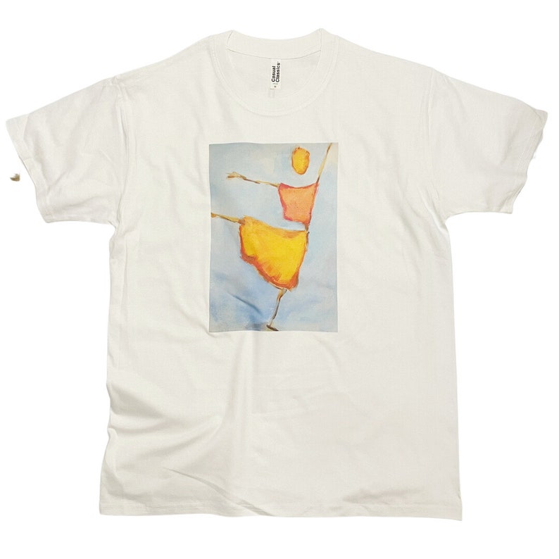 Op de afbeelding: Wit T-shirt met een grafische print van een gestileerde figuur in geel en rood, dansend tegen een blauwe achtergrond.