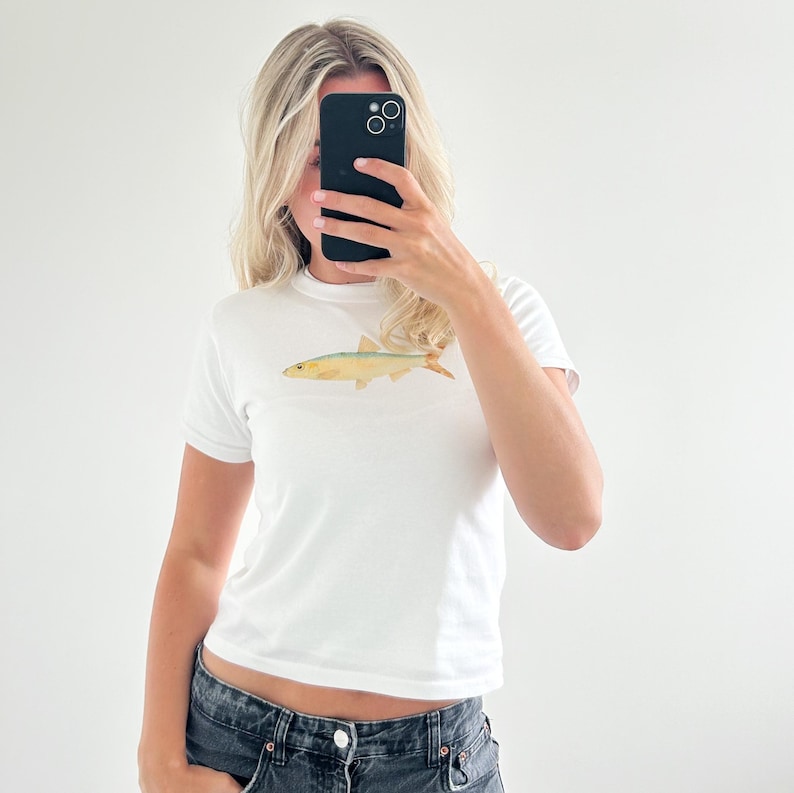 May include: White cropped t-shirt with a small, yellow fish illustration on the front.