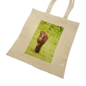 May include: A beige tote bag with a printed image of an orangutan holding a baby orangutan in a green jungle setting.