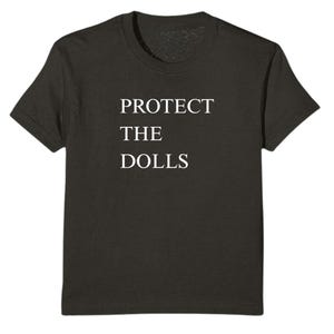 May include: A dark gray t-shirt with the text "PROTECT THE DOLLS" printed in white.