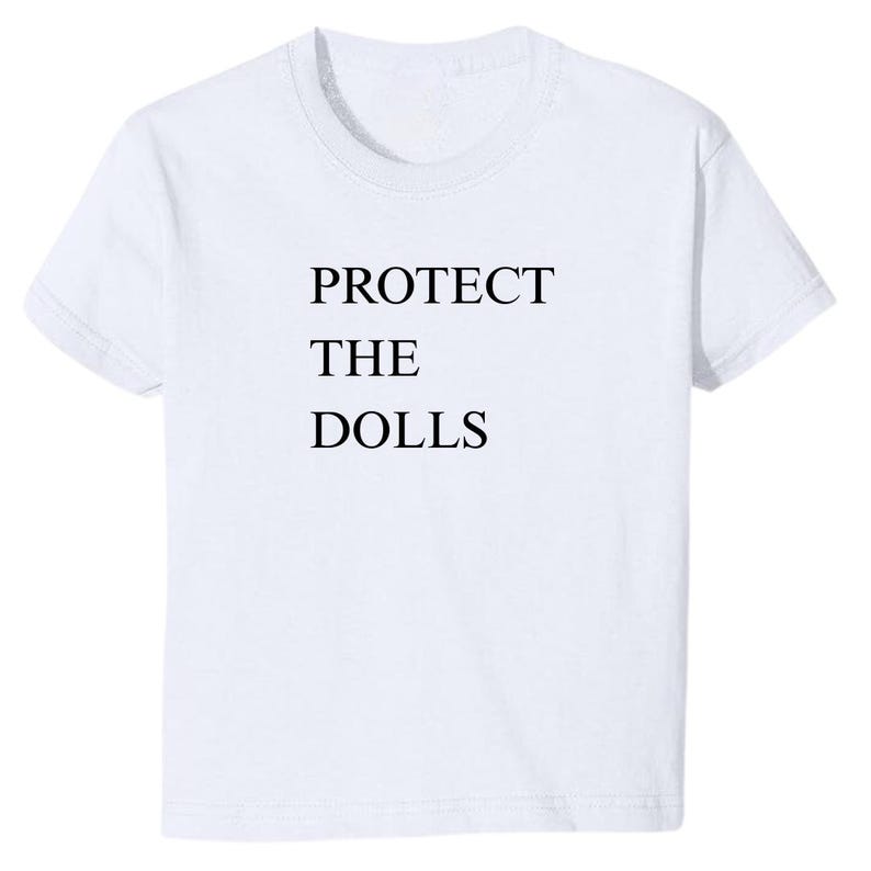 May include: White t-shirt with black text that reads "PROTECT THE DOLLS".