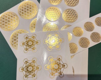 May include: A sheet of gold foil stickers with geometric designs. The stickers feature a flower of life pattern and a sacred geometry pattern.