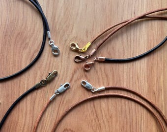 May include: Four leather cords with silver clasps. Two cords are brown and two are black.
