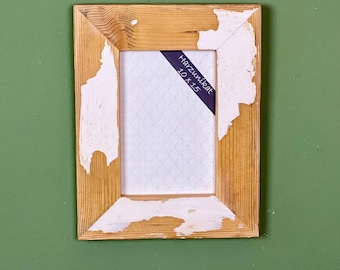 Peut inclure: Un cadre photo en bois rustique avec de la peinture blanche écaillée, laissant apparaître le bois en dessous. Le cadre mesure 10 x 15 pouces et porte une étiquette indiquant "Harzubehör".