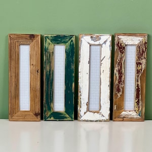May include: Four rectangular wooden frames arranged side by side. The first frame is natural wood grain, the second is painted green with visible brushstrokes, the third is distressed white, and the fourth is weathered wood with patches of white paint.