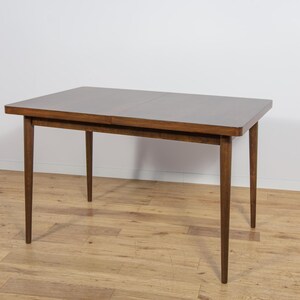 Könnte beinhalten: Ein rechteckiger Esstisch aus Holz mit einer dunkelbraunen Tischplatte und vier sich verjüngenden Beinen. Der Tisch ist etwa 122 cm lang und 76 cm breit, mit einer Höhe von etwa 76 cm. Der Tisch steht vor einer weißen Wand und einem Holzboden.