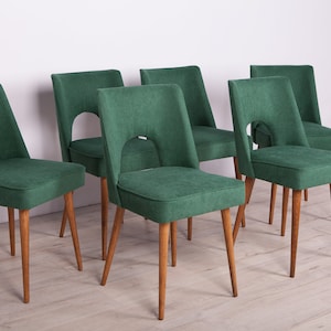 May include: Set of six green dining chairs with wooden legs. The chairs feature a distinctive cut-out design in the back.