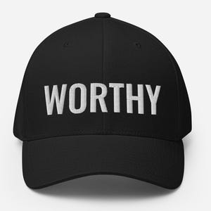 May include: Black baseball cap with the word "WORTHY" embroidered in white across the front. The cap has a curved brim and a structured fit. A simple, yet bold accessory.