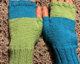 Könnte beinhalten: Ein Paar Fingerlose Handschuhe mit einem grün-blauen Farbblock-Design. Die Handschuhe sind gestrickt und haben einen gerippten Bund.