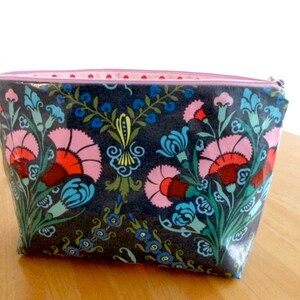 May include: A gray zippered pouch with a floral print featuring pink, red, blue, and green flowers on a dark gray background.