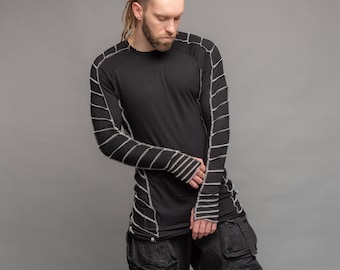 Puede incluir: Camiseta negra de manga larga con detalles de costura blanca en las mangas y los hombros. La camiseta tiene un corte holgado y cuello redondo.