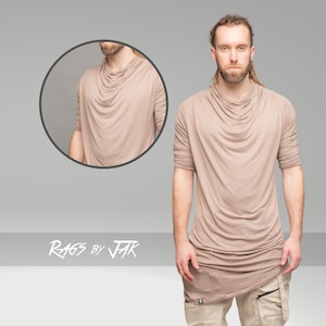 May include: A long-sleeved, light brown, draped t-shirt with a cowl neck. The t-shirt is made of a soft, stretchy fabric and has a relaxed fit. The text "RAGS BY JAK" is visible at the bottom of the image.