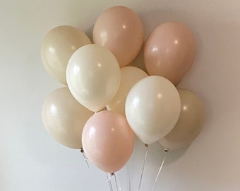 Może przedstawiać: Gromada kremowych, różowych i beżowych balonów związanych razem przezroczystą wstążką. Balony są ułożone w kształt półkola.