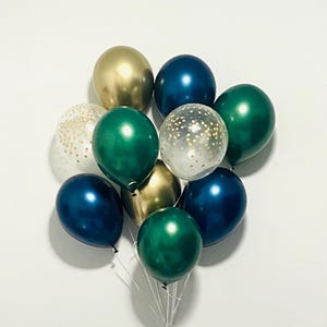 May include: A cluster of ten balloons in various colors, including gold, emerald green, and navy blue. Two balloons are clear with gold confetti. The balloons are tied together with white string, perfect for a celebration.