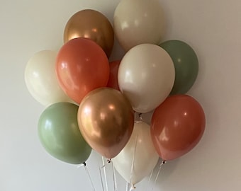 Könnte beinhalten: Ein Bündel Ballons in verschiedenen Grüntönen, Creme und Orange. Die Ballons sind mit weißen Schnüren zusammengebunden.