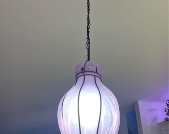 May include: A white and pink glass pendant light with a black metal frame and chain. The light is shaped like a teardrop and has a white frosted glass shade.