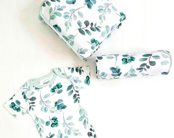 May include: A baby bodysuit, a small pillow, and a swaddle blanket, all featuring a white background with a green leafy pattern.