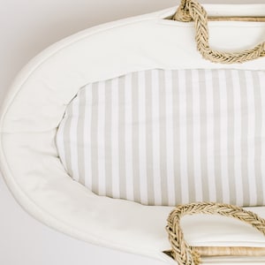 Peut inclure: Un panier en osier blanc de forme ovale avec une doublure rayée blanche et grise. Le panier a deux poignées en corde.