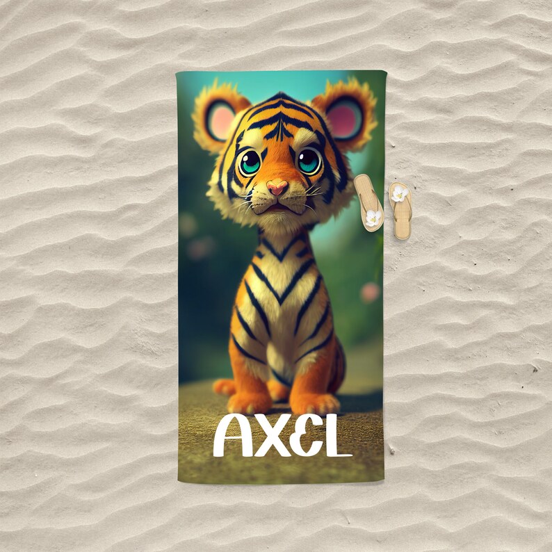 Op de afbeelding: Een strandhanddoek met een cartoon-tijgerillustratie en de naam "AXEL" in witte letters.