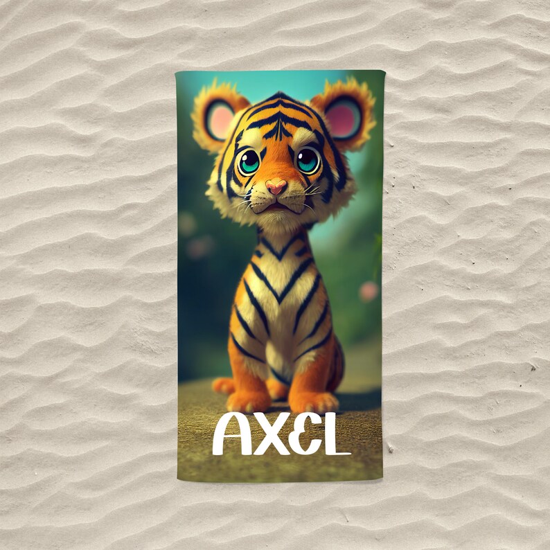 Op de afbeelding: Een strandhanddoek met een cartoon-tijgerillustratie en de naam "AXEL" onderaan gedrukt.