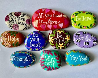 May include: A collection of ten smooth, hand-painted river stones featuring colorful designs and inspirational text including Do more with less, All you need is Love, Believe, Hope, Do your best, Be Kind, Smile, Strength, Why not?, and Yay You!