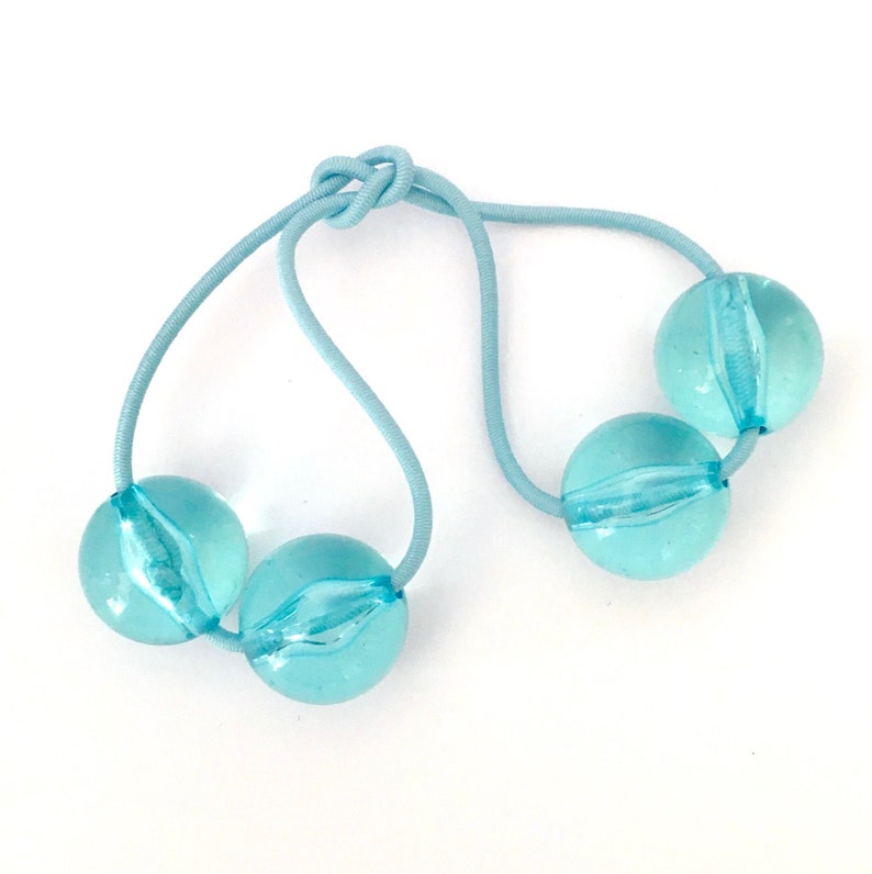 May include: A light blue hair tie with three light blue, translucent, round beads.