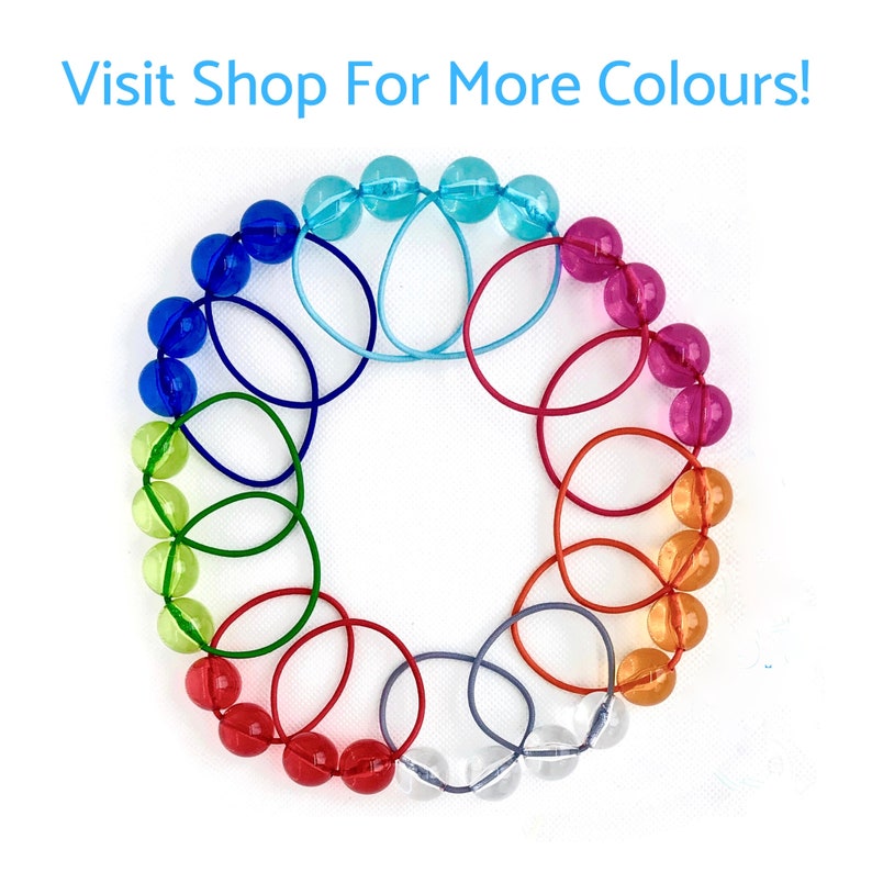 May include: A rainbow of colors in a circle of rubber bands. The rubber bands are connected to each other, creating a circular pattern. The text "Visit Shop For More Colours!" is written in blue at the top of the image.