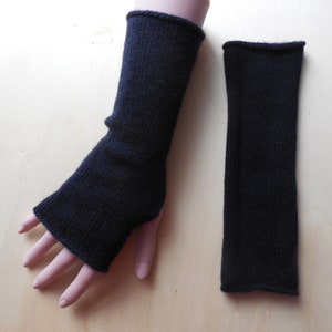 Könnte beinhalten: Ein Paar schwarze fingerlose Strick-Armwärmer. Die Armwärmer sind aus einem weichen, dehnbaren Stoff gefertigt und perfekt, um Ihre Hände im Winter warm zu halten.