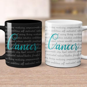 May include: Two ceramic coffee mugs with black and white backgrounds. The mugs feature the word "Cancer" in teal text surrounded by a description of the zodiac sign's personality traits.