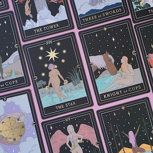 May include: A set of tarot cards with black backgrounds and gold accents. The cards feature illustrations of people, animals, and symbols. The cards are arranged in a grid pattern on a pink surface. The cards include The Tower, Three of Swords, Knight of Cups, The Star, Wheel of Fortune, and Three of Wands.