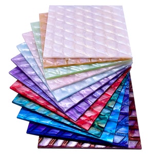 May include: A stack of iridescent, textured sheets in various colors, including purple, blue, green, and pink. The sheets have a diamond-shaped pattern and are made of a pearlescent material.