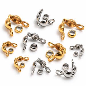 May include: A collection of gold and silver-toned metal clamshell bead tips, also known as knot covers, each paired with a small matching crimp bead. These jewellery findings feature a hinged design with two loops for attaching clasps or jump rings.