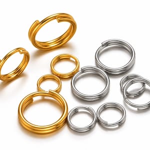 May include: A collection of circular split rings in various sizes, featuring a metallic finish in both gold and silver tones. Each ring is constructed from a double-layered wire coil, creating a sturdy loop for attaching keys or small items.