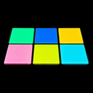 Pode incluir: Um conjunto de seis painéis quadrados e planos dispostos numa grelha de dois por três contra um fundo preto. Os painéis são de cores vivas em verde néon, azul, amarelo, rosa, verde lima e ciano, emitindo um efeito de luz vibrante.
