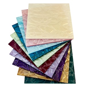 Może przedstawiać: Stosik dziesięciu dekoracyjnych arkuszy z tworzywa sztucznego z fakturowanym wzorem kwiatowym. Arkusze są w różnych kolorach, w tym zielonym, niebieskim, fioletowym, złotym i czerwonym.