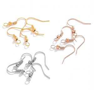 Peut inclure: Divers crochets de boucles d'oreilles en or, or rose et argent. Les crochets ont un design incurvé avec une petite boule et un détail de ressort hélicoïdal. Les boucles d'oreilles sont présentées sur fond blanc.