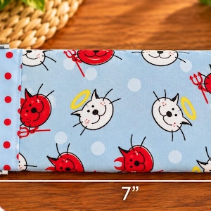 May include: A rectangular fabric eyeglass case featuring a light blue background with a repeating pattern of red devil cats and white angel cats. A red and white polka dot fabric strip accents the left side. It measures 3.5 inches by 7 inches.