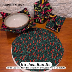 May include: A kitchen bundle featuring a bowl cozy, tortilla warmer, pot holders, and coasters. The items have a black background with a pattern of red and yellow chili peppers and green leaves. The text "Kitchen Bundle" is visible.