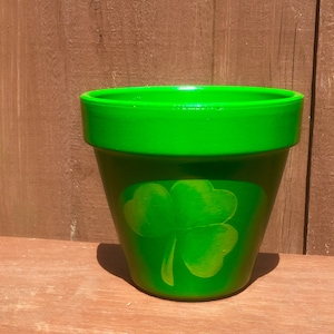 Può includere: Un vaso di terracotta verde con un design a trifoglio. Il vaso è perfetto per aggiungere un tocco di fascino irlandese alla tua casa.