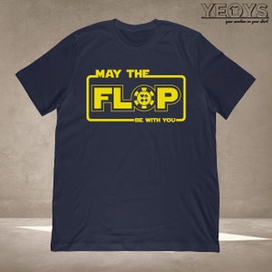 Puede incluir: Una camiseta azul marino con un gr&aacute;fico amarillo que dice "Que el Flop est&eacute; contigo". El gr&aacute;fico presenta una ficha de p&oacute;quer amarilla con una pica, un coraz&oacute;n, un diamante y un tr&eacute;bol negros.