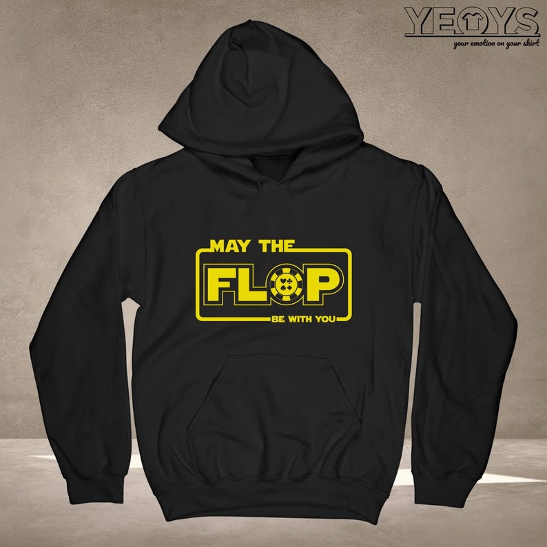 Puede incluir: Sudadera con capucha negra con un gr&aacute;fico amarillo que dice "Que el Flop est&eacute; contigo" con un s&iacute;mbolo de ficha de p&oacute;quer.