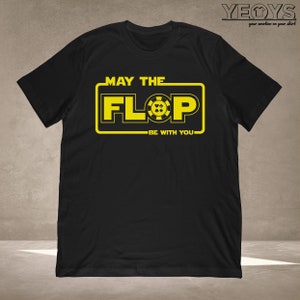 Puede incluir: Camiseta negra con un gr&aacute;fico amarillo que dice "Que el Flop est&eacute; contigo". El gr&aacute;fico presenta una ficha de p&oacute;quer con cuatro palos de cartas.