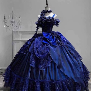 May include: A dark blue ball gown with a layered skirt and bodice. The dress features a large bow at the waist and decorative ruffles. The gown is displayed on a mannequin.