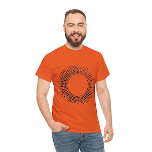 May include: An orange t-shirt featuring a black dotted circle design. The short-sleeved shirt is made of a soft material and is being worn with blue jeans. The design is centered on the chest.