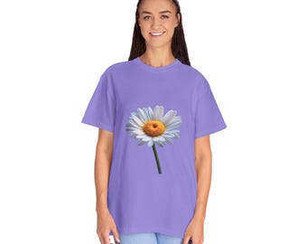 以下が含まれることがあります： 大きなデイジーがプリントされたライラック色のTシャツ。 デイジーは白い花びらと黄色の中心部、緑色の茎があります。 Tシャツはカジュアルなスタイルで、普段使いに適しています。